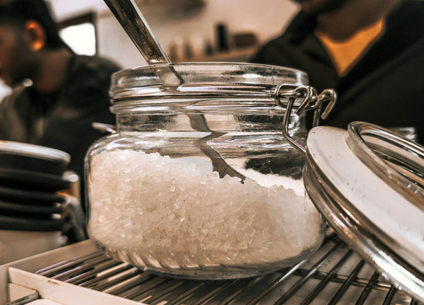 A glass jar of creatine powder with a metal scoop, showing the airtight, moisture-free storage that determines whether creatine expires or stays potent.