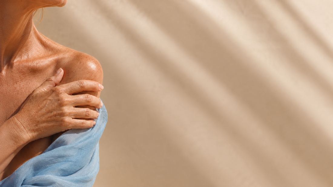 Close-up of an older woman's shoulder and hand in warm light, healthy aging