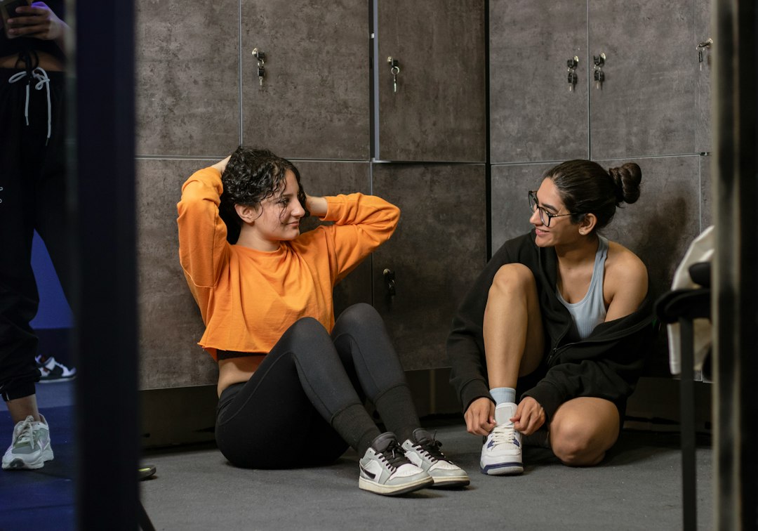 Two athletes tie their shoes in the locker room as they get ready to train again after a recovery day, illustrating how creatine and recovery work together to get you back in the gym sooner.
