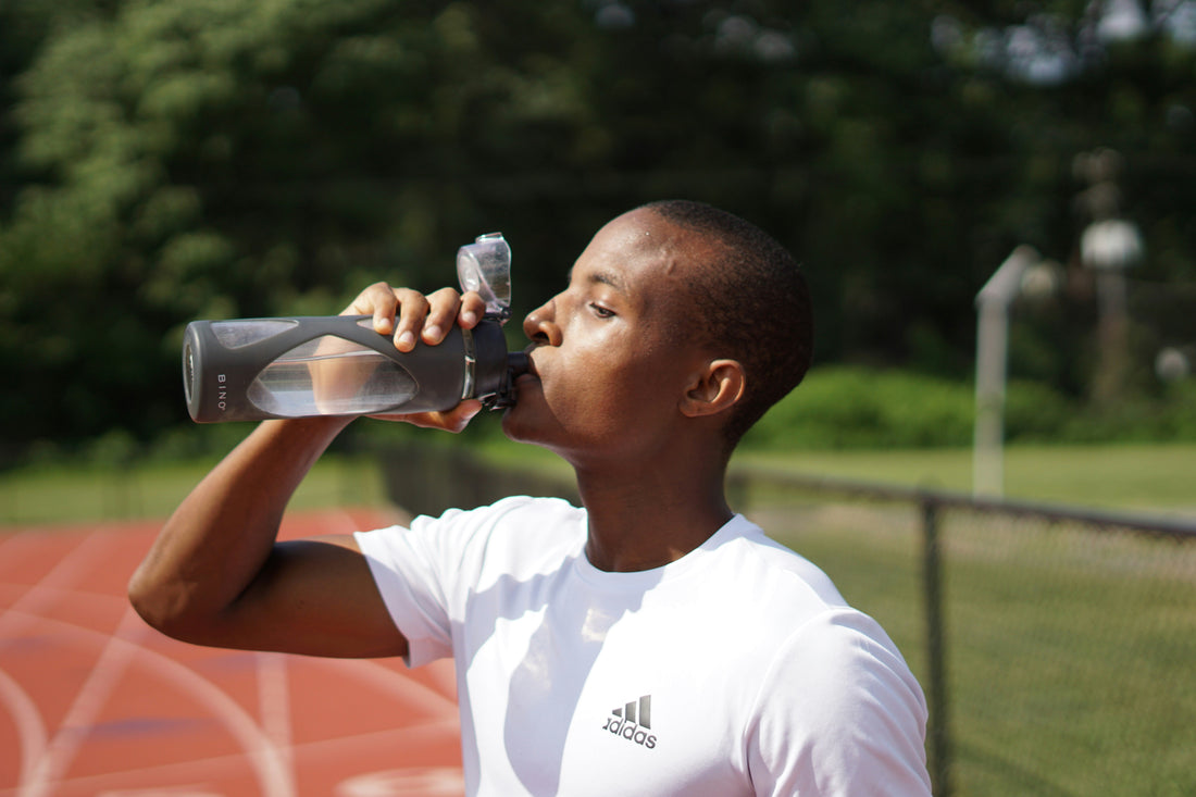A man drinks from a water bottle mid-workout, illustrating why testing your sweat rate at home helps you replace fluids lost during exercise.