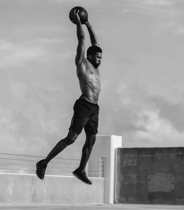A man leaps explosively during a high-intensity interval training workout outdoors, illustrating how much sweat and electrolytes HIIT sessions demand from active adults.