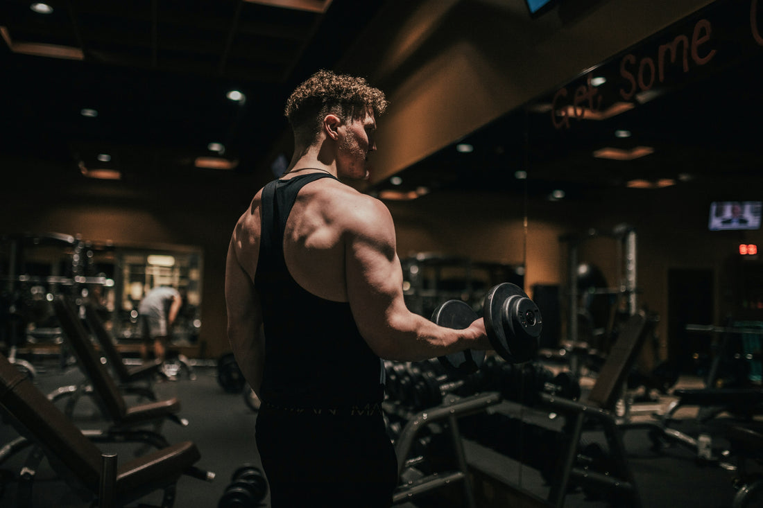 A man performs a dumbbell exercise in the gym, the kind of consistent strength training where getting your creatine dosing right, just 3 to 5 grams a day, makes the biggest difference over time.