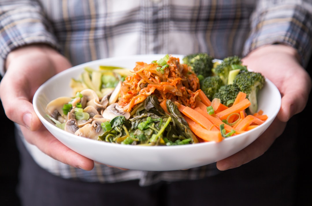 A person holding a plate of fresh vegetables, representing the vegetarian and vegan diet that leaves less dietary creatine to work with.