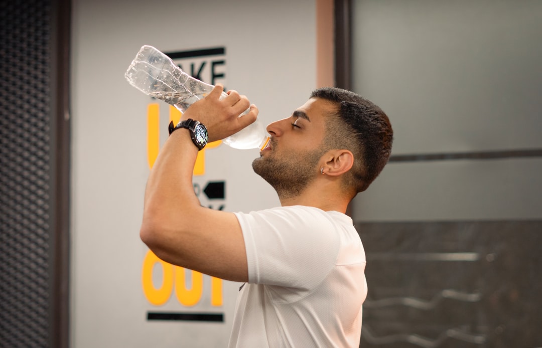A man drinking water from a bottle during a gym workout