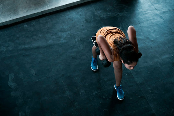 A woman lifts weights during an indoor strength workout, representing the active adults who need smarter hydration advice than just drink more water.