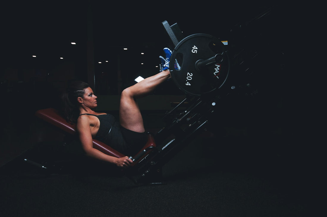 A woman performs strength training on gym equipment, the kind of active routine where staying on top of electrolytes on a low-carb or fasting diet keeps her energy steady.