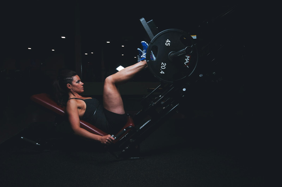 A woman performs strength training on gym equipment, the kind of active routine where staying on top of electrolytes on a low-carb or fasting diet keeps her energy steady.