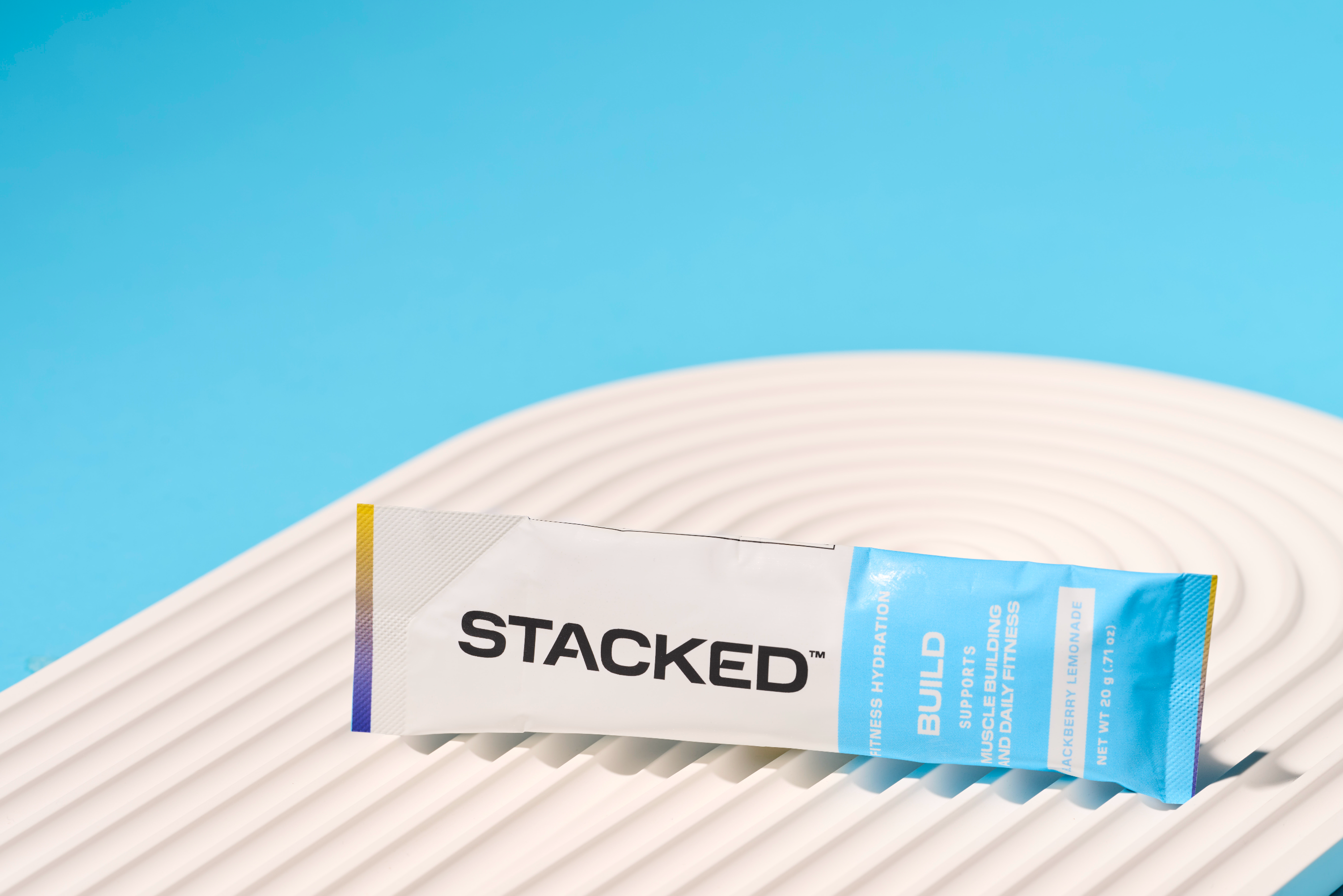 Stacked: BUILD sachet packaging on a white surface with a blue background