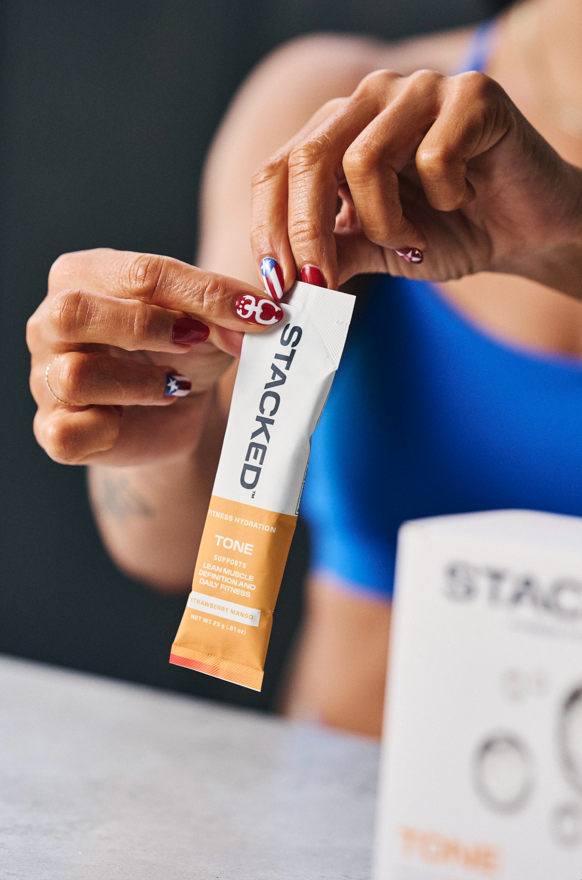 Person holding a 'Stacked' hydration powder packet with a blurred background