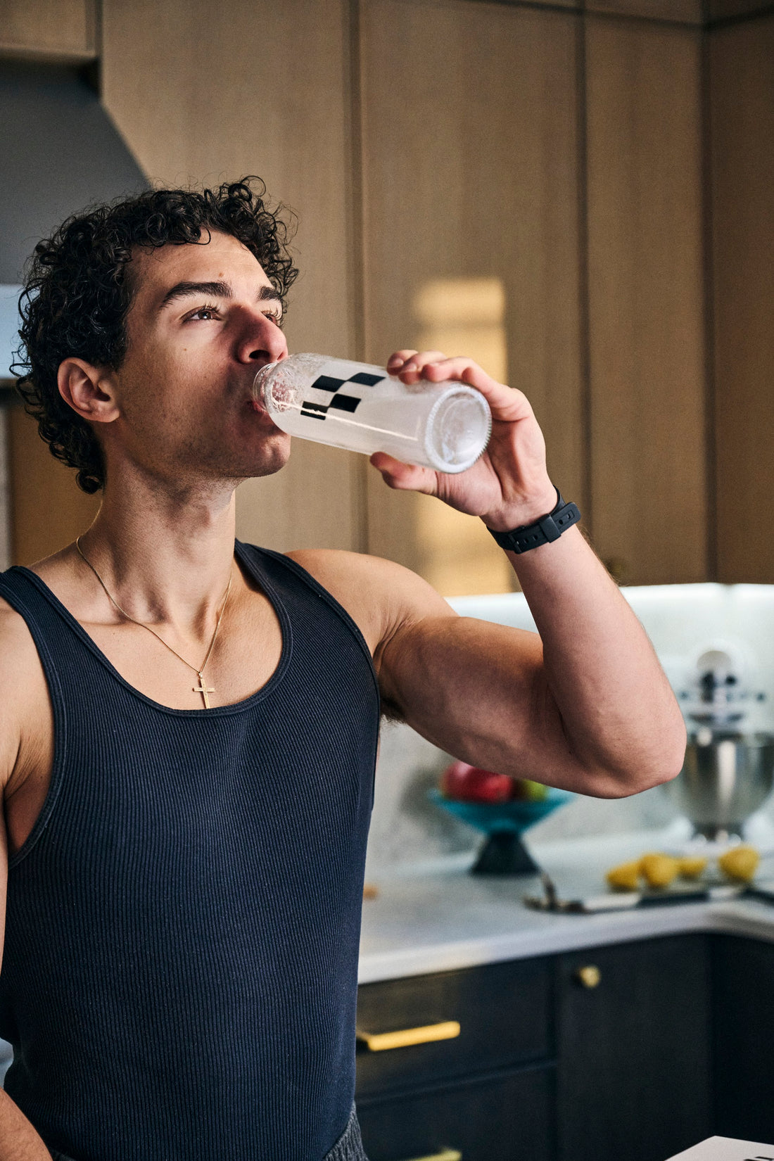 Man drinking from a Stacked water bottle in his kitchen