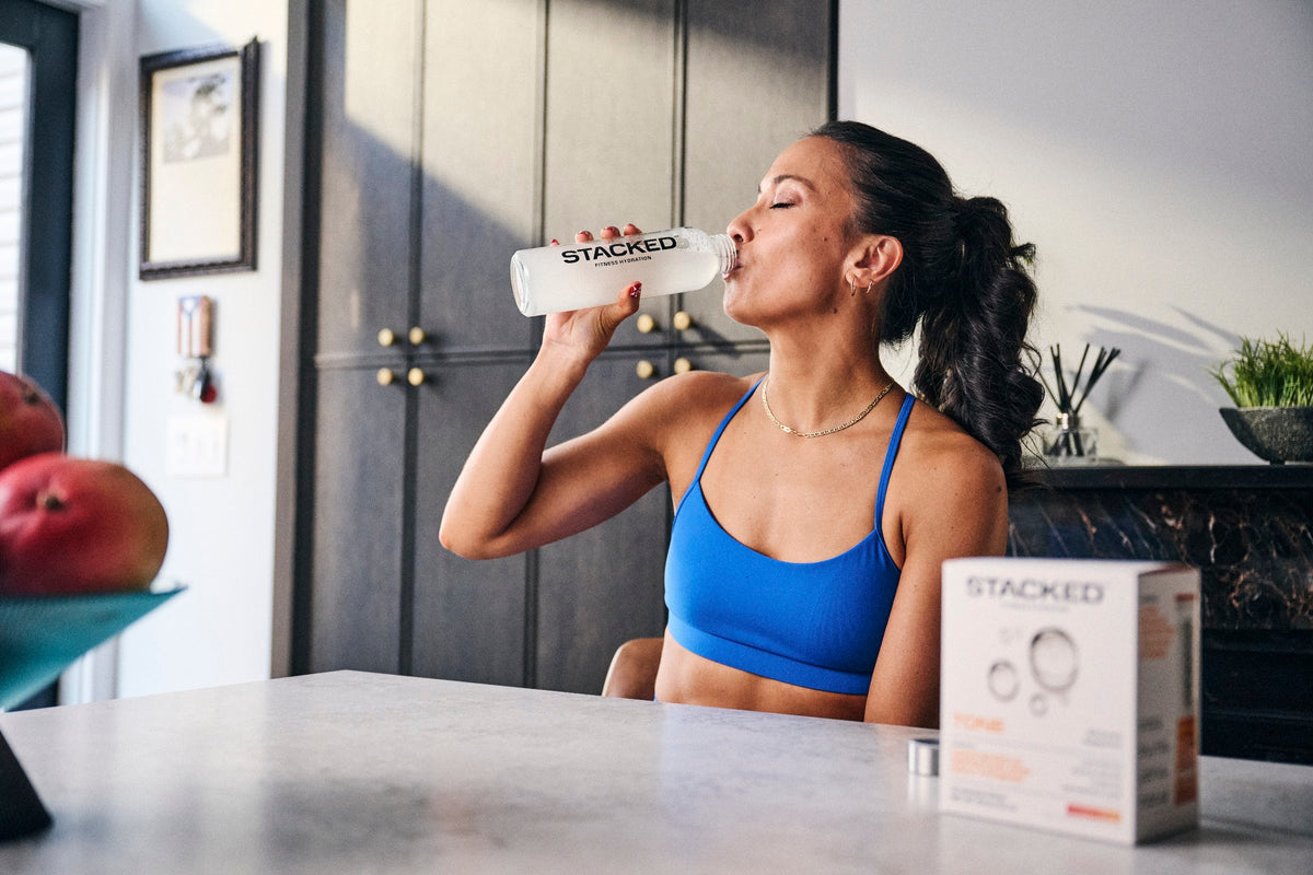 Woman drinking from her Stacked water bottle at the kitchen table